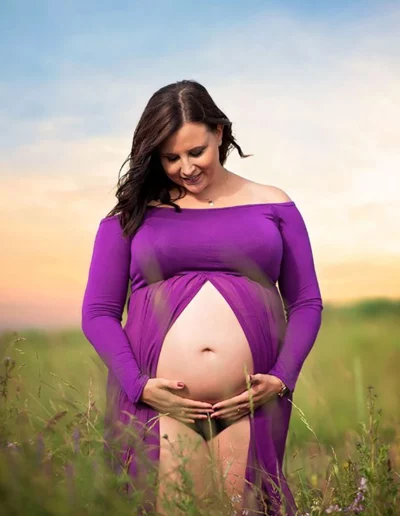 Babybauch-Fotoshooting im Freien - Schwangere Frau im lila Kleid bei Sonnenaufgang in der Natur